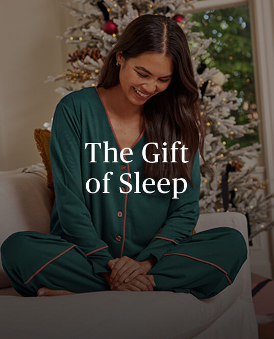 The Gift of Sleep copy over an image of a smiling brunette woman wearing the Summersalt Cloud 9 Pajama Set