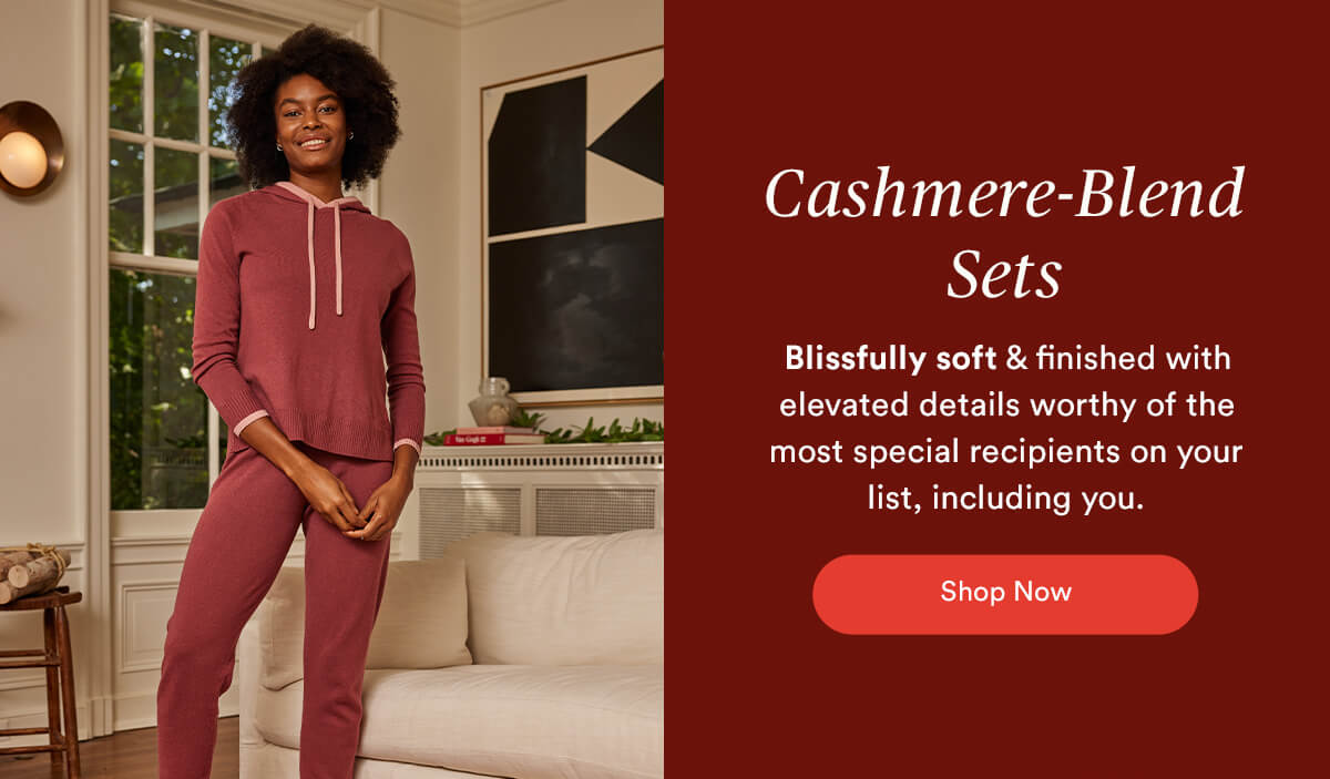 Cashmere Blend Sets. Image of a woman standing near a couch wearing our Coziest Cashmere-Blend Set in Rosewood.
