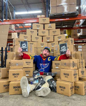 Troy with a pile of boxes and cases of 2021/22 Upper Deck The Cup Hockey