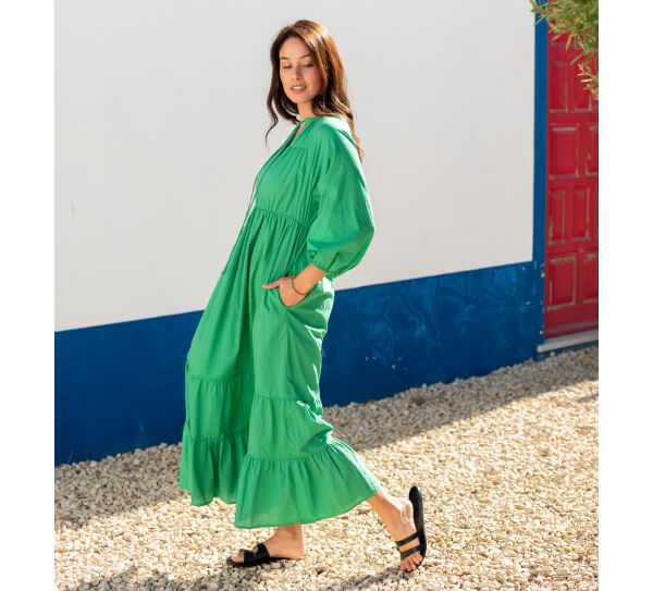 Image of woman wearing green tiered long sleeve maxi dress with hand in pocket