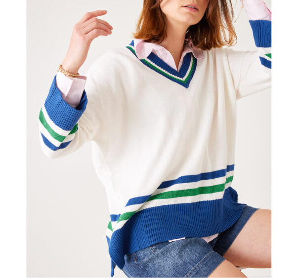 Image of a woman wearing a white v-neck sweater with blue and green stripes.