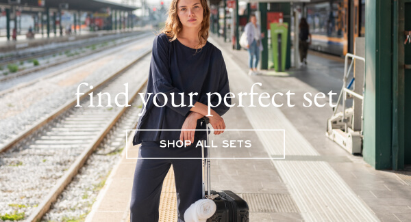 Find your perfect set - Shop all sets - Image of a woman at a train station wearing a navy long sleeve tee and matching pants