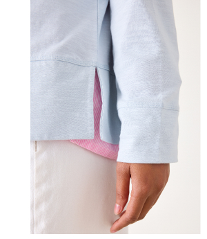 Close up of wide hem and side slit of a blue long sleeve tee