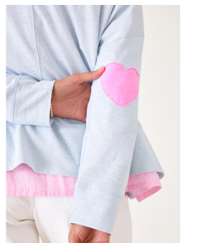 Close up of the pink heart patch on the elbow of a light blue long sleeve tee