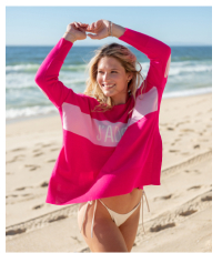 Image of a woman on the beach wearing a pink sweater that says j'adore