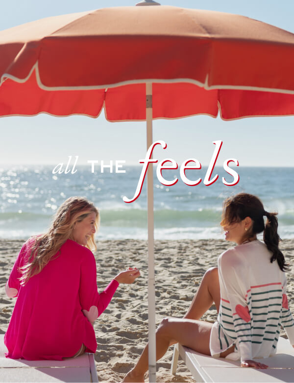 All the Feels - Image of two women on the beach wearing different color sweaters with heart patches on the elbows