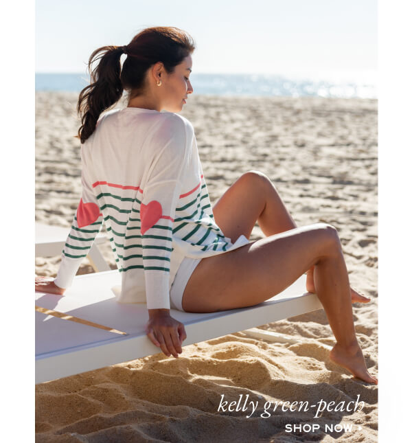 Image of a woman on a beach wearing a white sweater with peach and green stripes and peach heart patches on the elbows - Kelly Green-Peach - Shop now