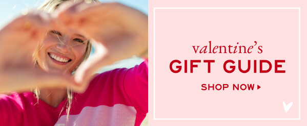 Valentine's Gift Guide - Shop Now - Image of a woman in a pink sweater making a heart shape with her hands