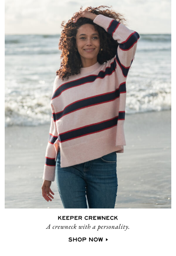 Keeper Crewneck - A crewneck with a personality. Shop Now. - Woman on beach wearing a pink sweater with navy and red stripes