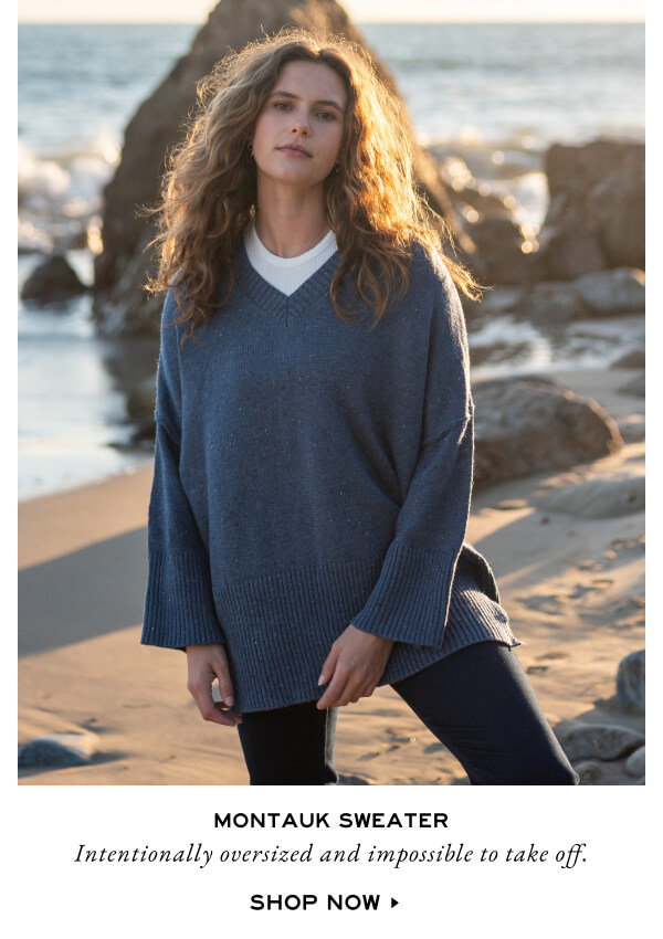 Montauk Sweater - Intentionally oversized and impossible to take off. Shop Now - woman on beach wearing blue v-neck sweater