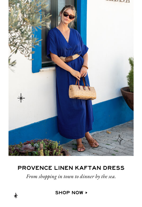 Provence Linen Kaftan Dress - From shopping in town to dinner by the sea. - Shop now - Image of a woman wearing a blue linen dress leaning against a wall