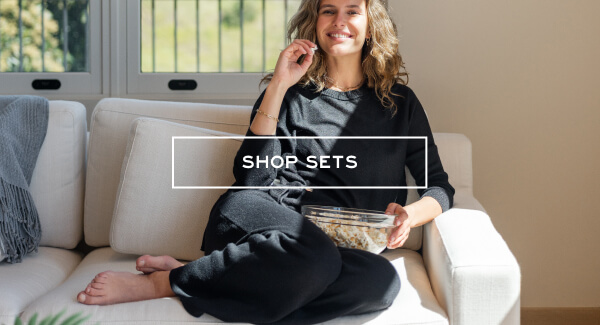 Shop Sets - Image of a woman sitting on a couch wearing a black sweater and matching pants