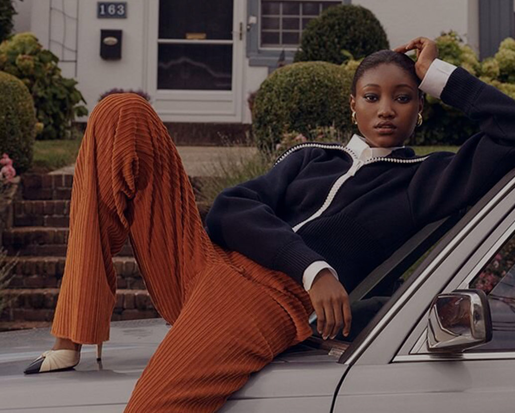 Woman in fall clothing posing on car