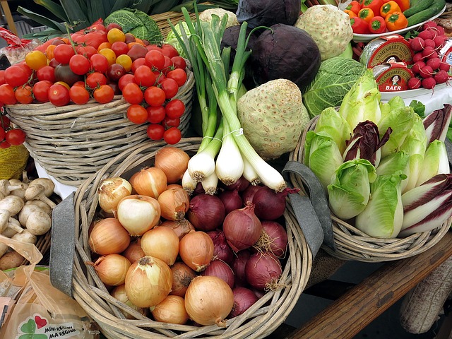 Baskets of vegetables, including tomatoes, sweet and red onions, green onions, cabbage, peppers, and mushrooms