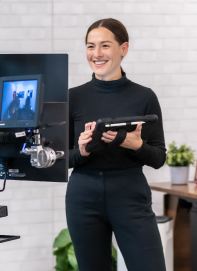 image of brandi smiling while holding a tablet and looking at a camera