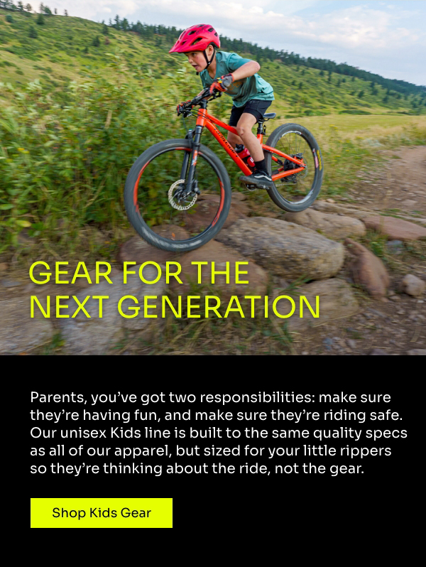 Young boy rides a red bike over some big rocks