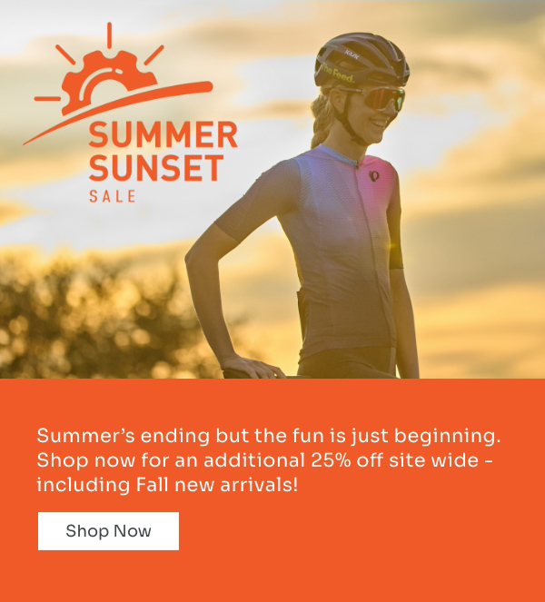 Hannah Shell standing next to her bike at sunset wearing a pastel rainbow jersey at sunset