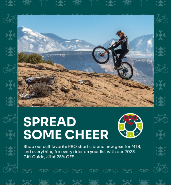 A mountain biker pops a wheelie in Moab with snow covered peaks in the background