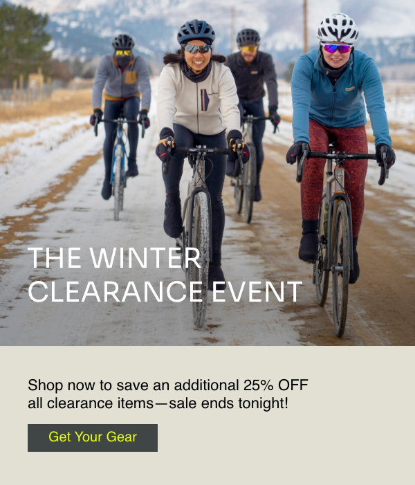A pack of cyclists ride a snow packed road.