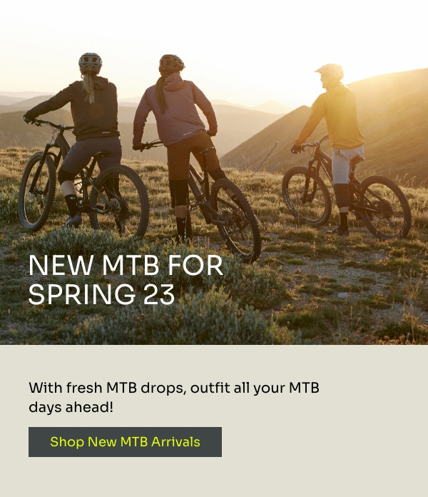 A group of 3 riders stop on their mountain bikes to enjoy a hilltop sunset.