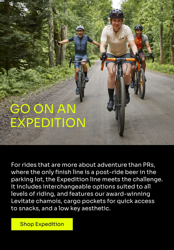 Three riders on a forested gravel road ride toward the camera